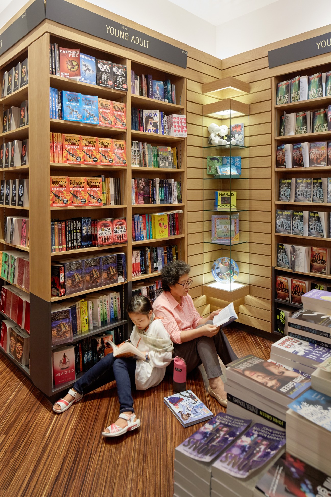 Two people reading books in the young adult section of Kinokuniya bookstore at Ngee Ann City in Singapore.