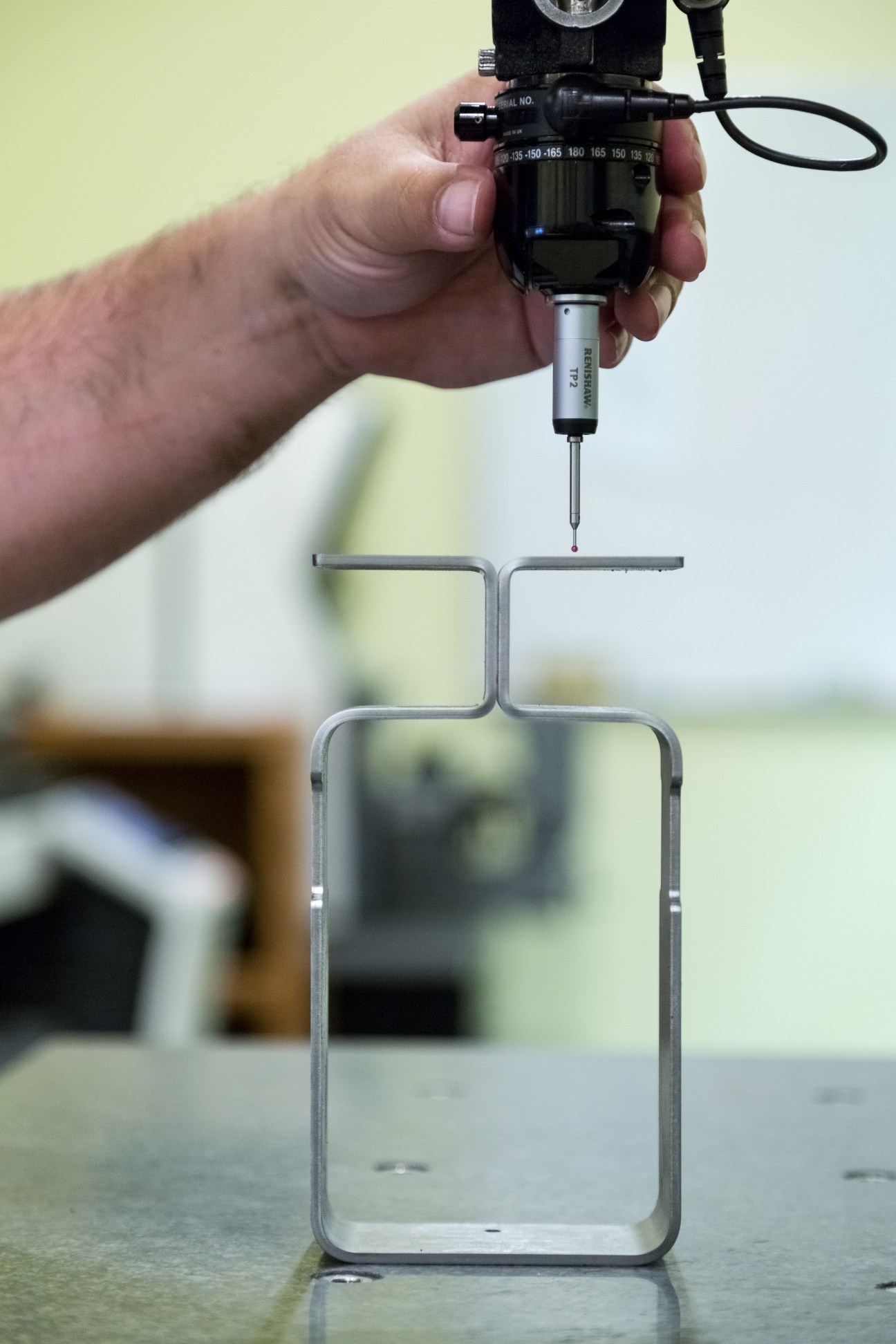 Hand holding precision measuring instrument above Floyd furniture leg component