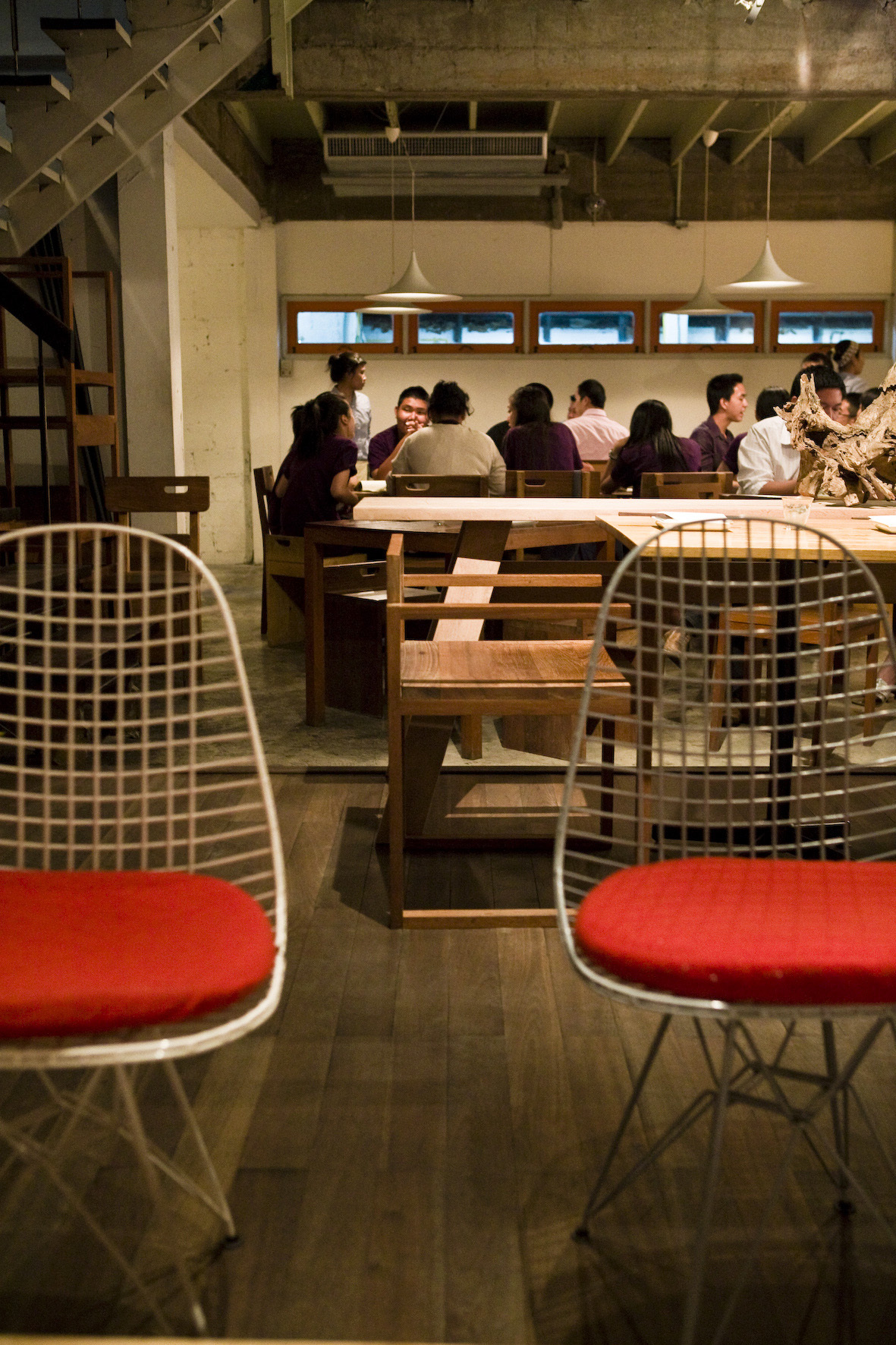 Interior of PlaDib restaurant with diners seated at long wooden tables under pendant lights.
