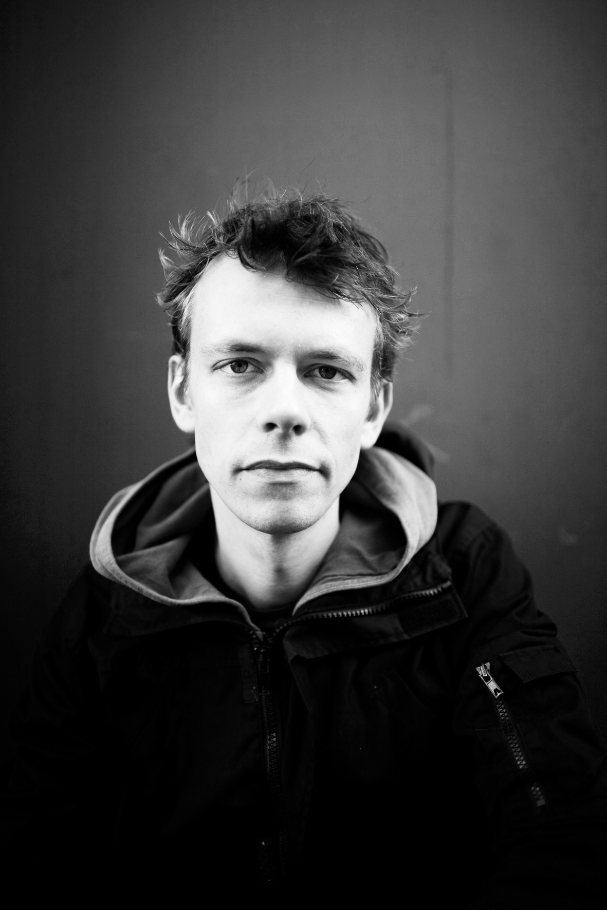 Black and white portrait of Rob Hornstra, a documentary photographer wearing a hooded jacket.