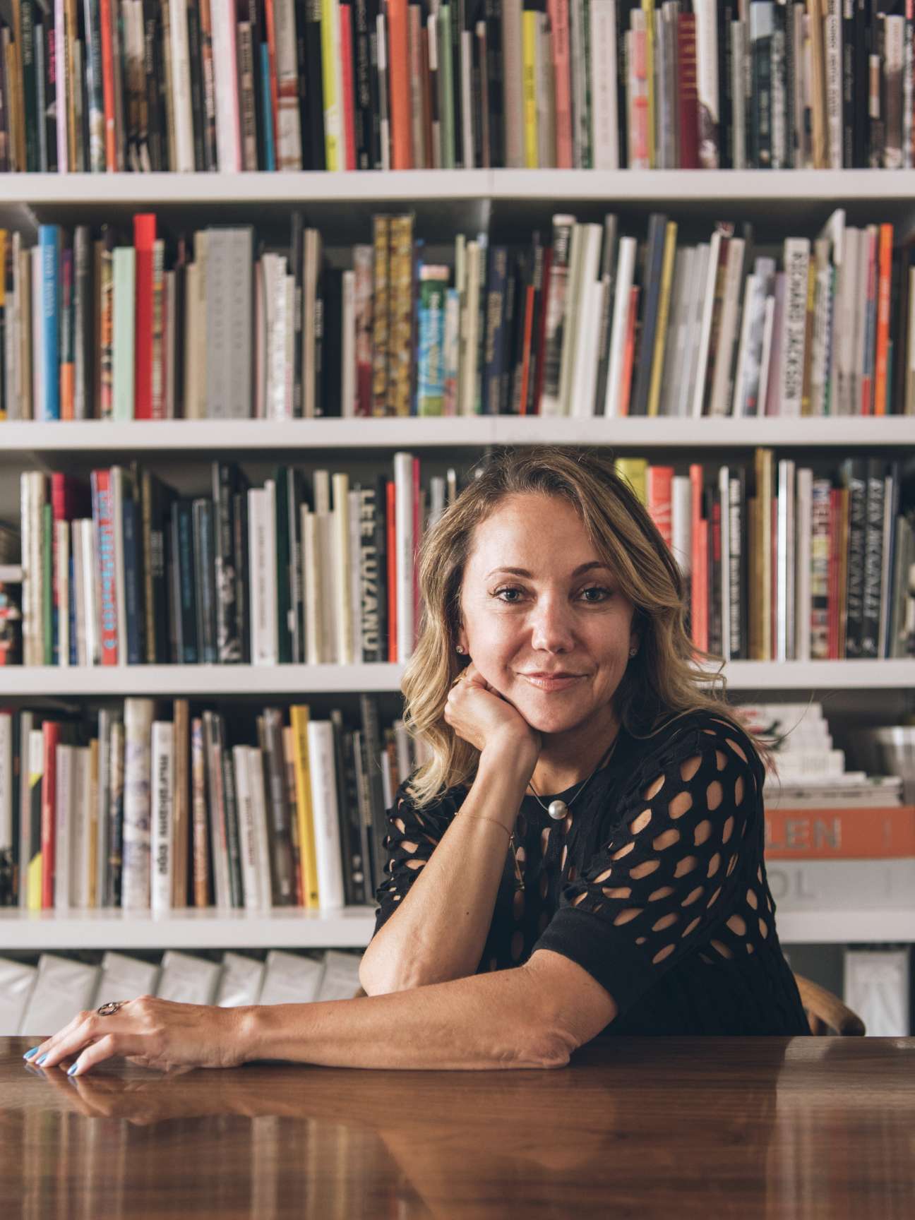 Art adviser Lisa Schiff poses at her desk with bookshelves behind her in her New York office.