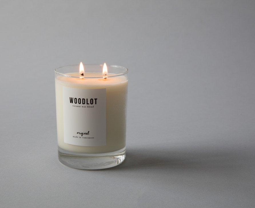 Lit Woodlot coconut wax blend candle with two flames in clear glass container