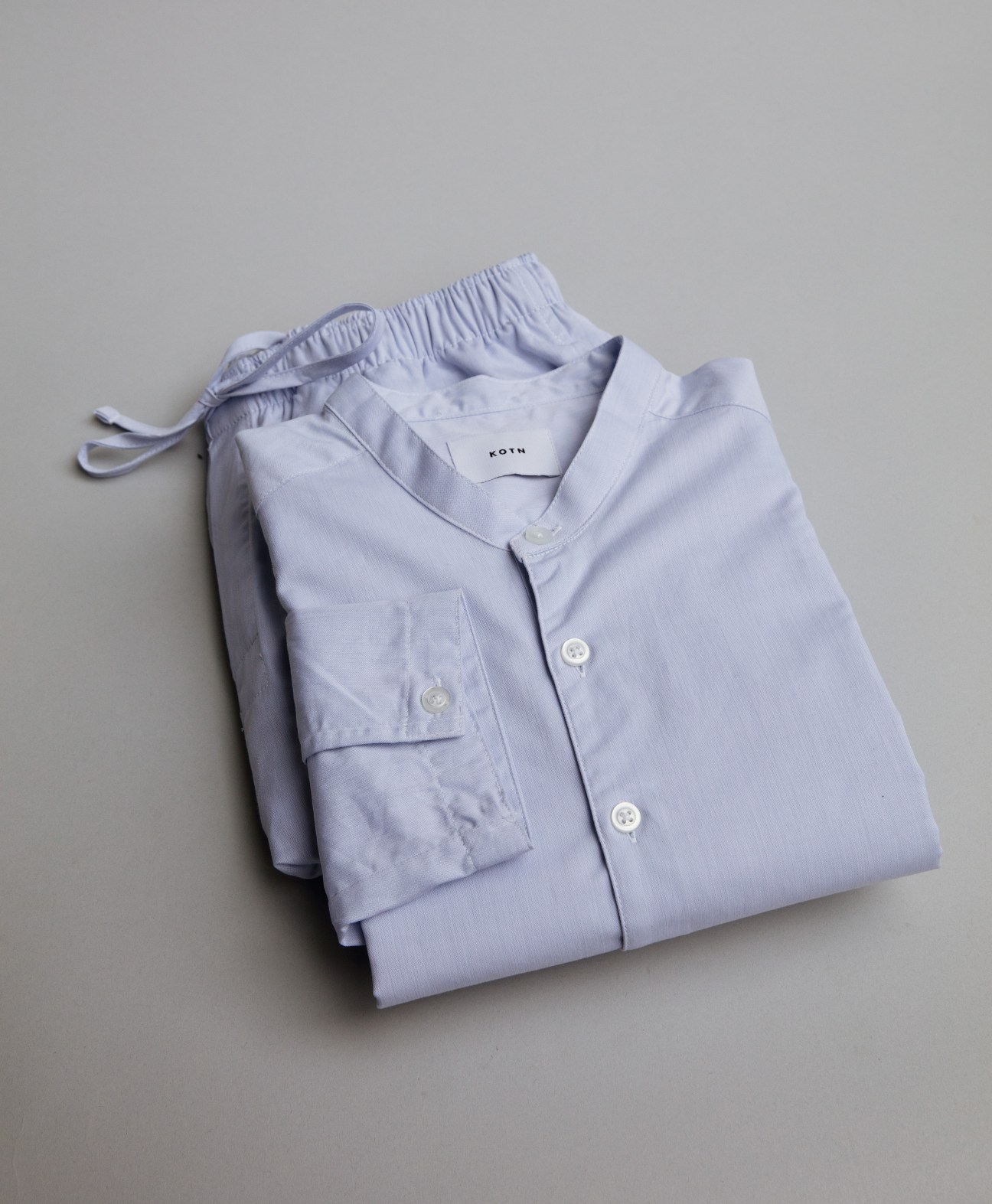 Light blue linen pajama set with button-front shirt and drawstring pants folded on beige surface