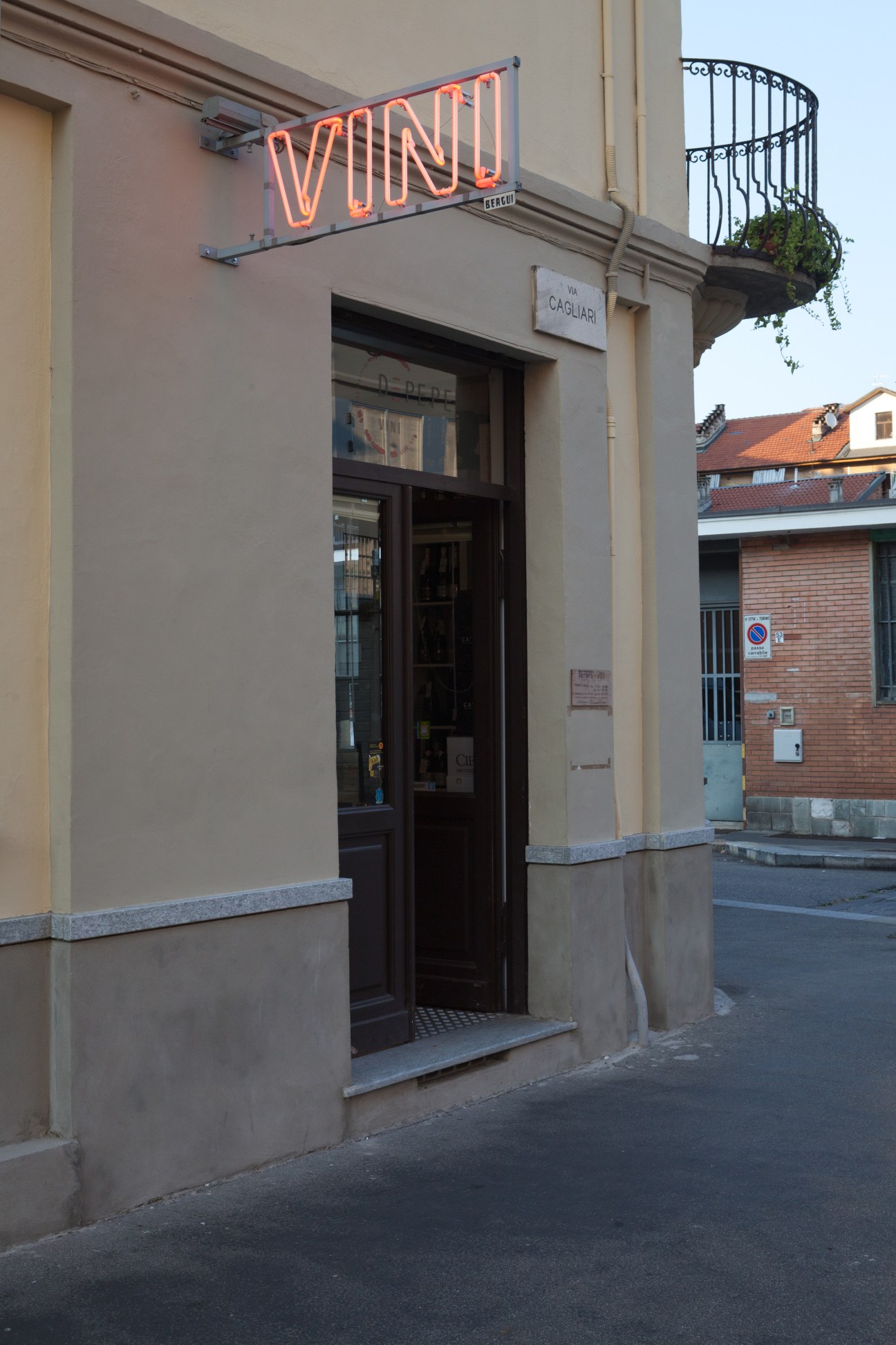 Storefront of Depepe enoteca with orange neon sign on a Turin street corner.