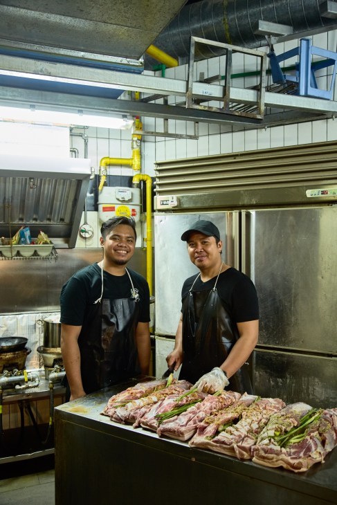 Two chefs in black aprons prepare raw meat dishes at Iskina Cebu kitchen counter.