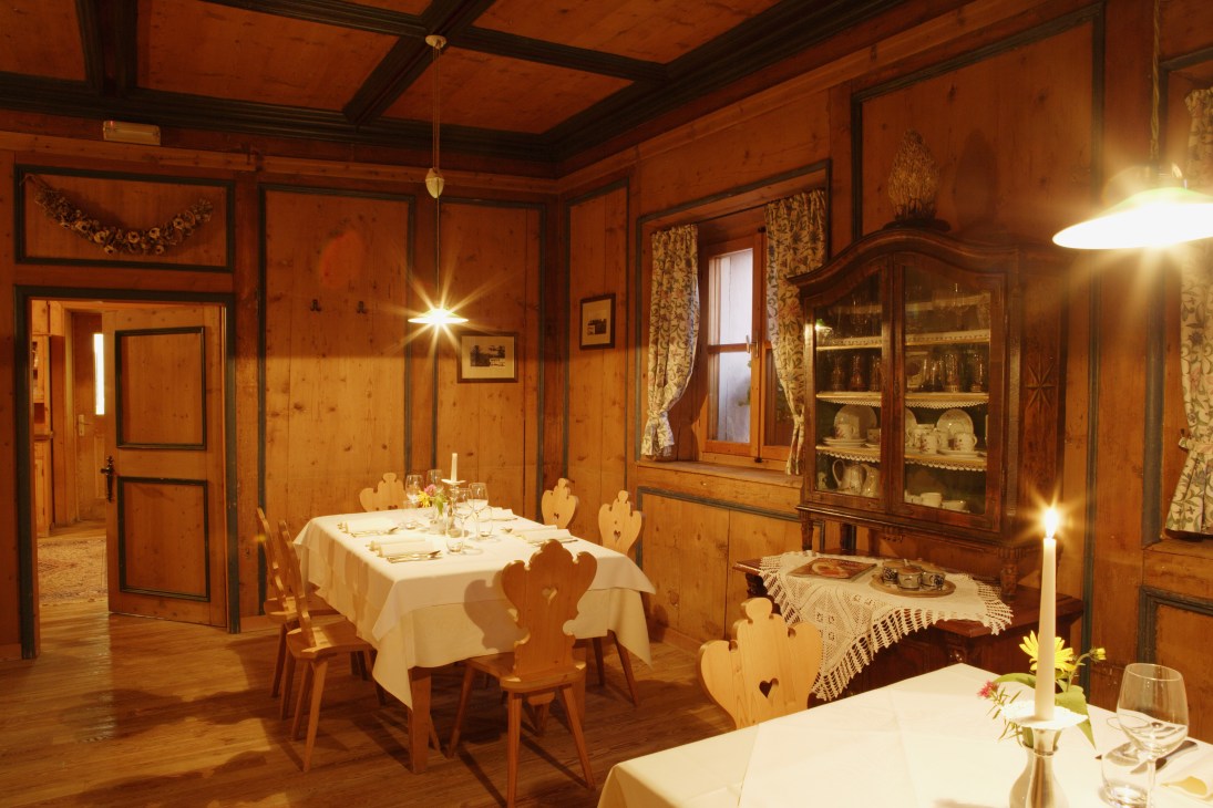 Traditional wood-paneled dining room at Gasthof Krone with set tables and antique furnishings.