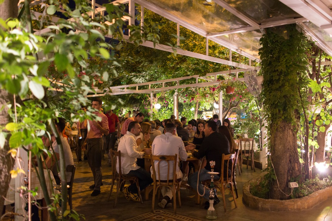 Al Falamanki restaurant in Beirut with diners seated under a leafy garden pergola at night.