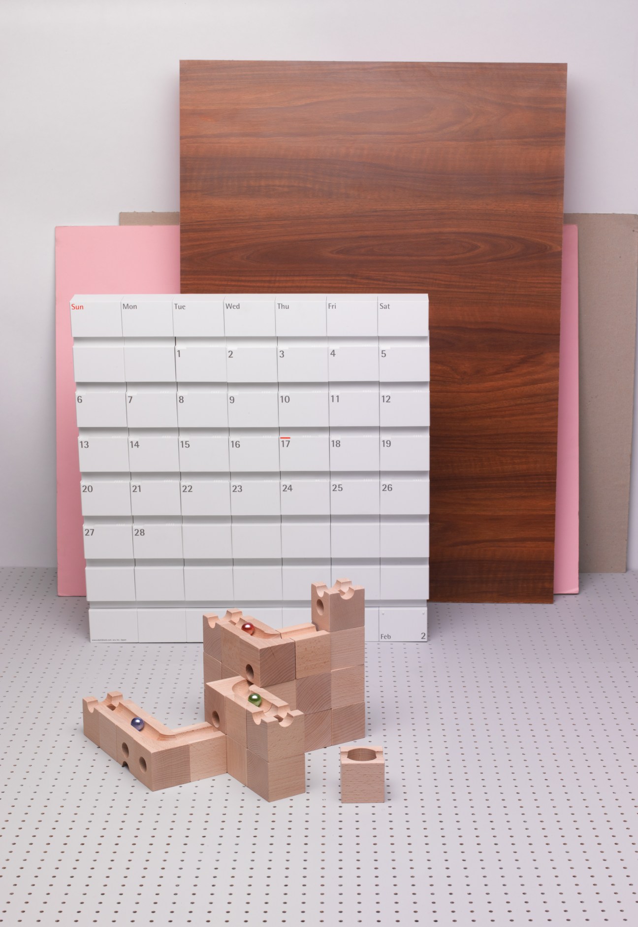 DateBlock wall calendar in pink with wooden panels and Cuboro beech wood marble run toy with colored marbles.