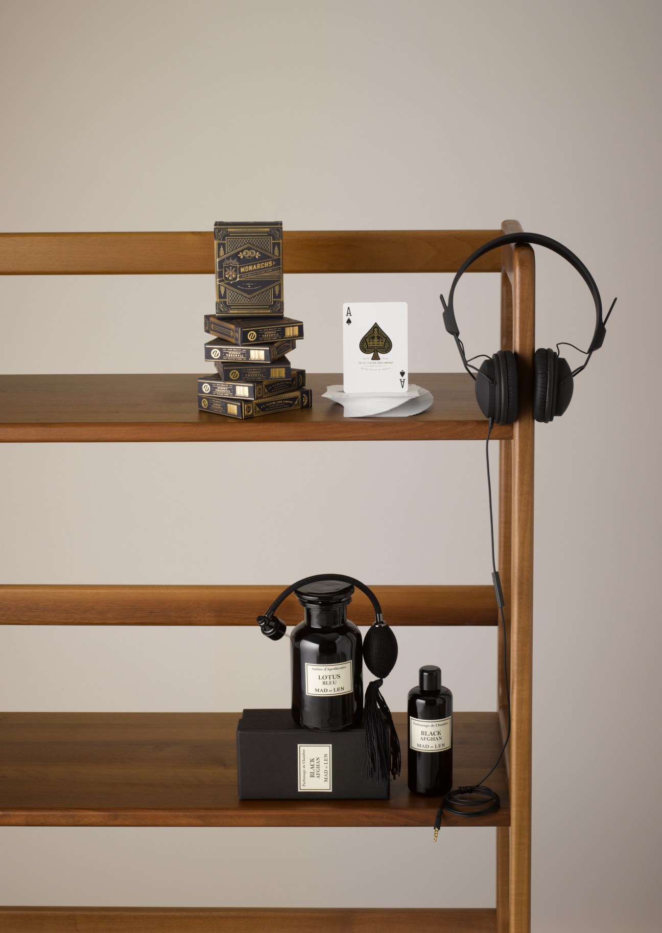Wooden shelving displaying Theory11 Monarch playing cards, Nocs headphones, and Mad et Len room perfume bottles.