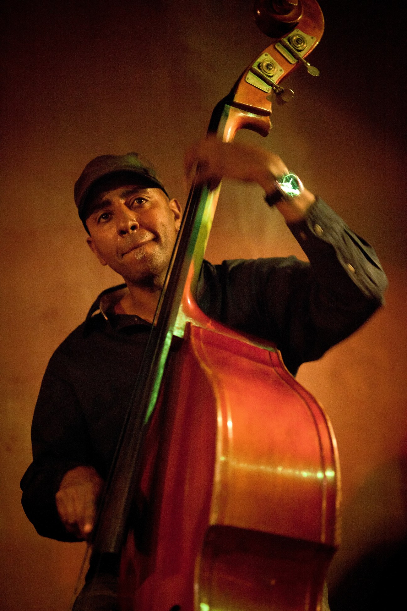 Henock Temesgen holds a red double bass against a warm golden background.