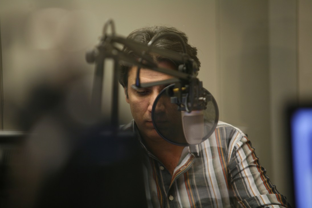 Broadcaster Qadir Habib speaking into a microphone in a recording studio.