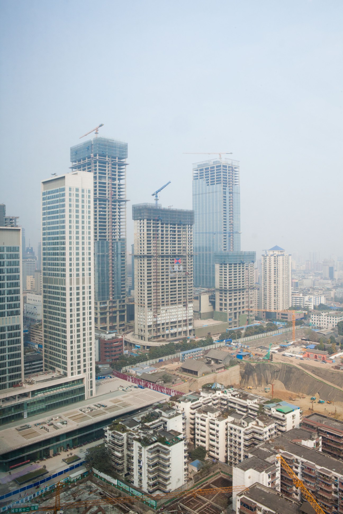 Aerial view of Chengdu's downtown skyline with multiple high-rise buildings under construction in hazy conditions.
