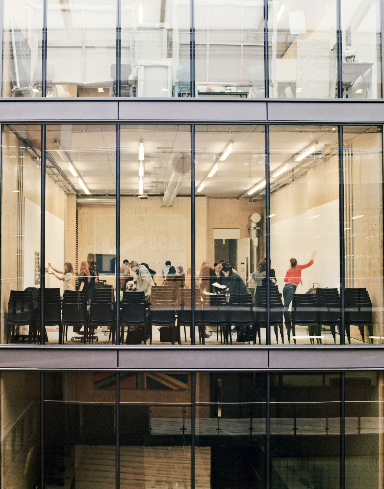 Students gather in a classroom visible through large floor-to-ceiling windows in the Granary Building at Central Saint Martins.