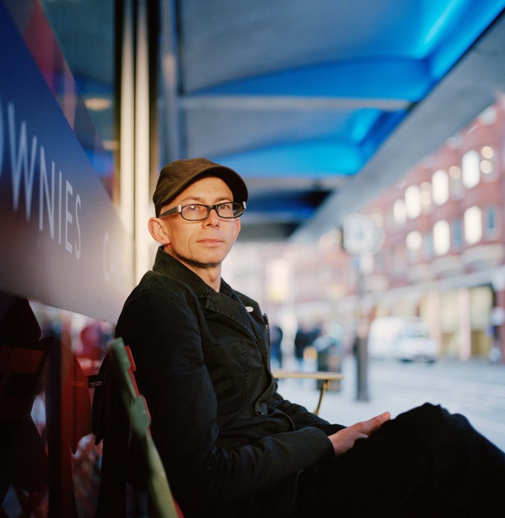 Jason Wood, programming director of Curzon Cinemas, wearing glasses and a dark cap in a cinema lobby.