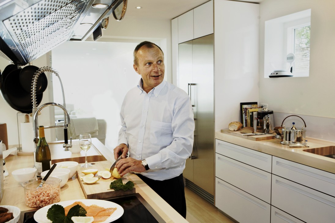 Jørgen Bodum prepares fjord shrimps in the kitchen of his Danish home, wearing a light blue shirt.