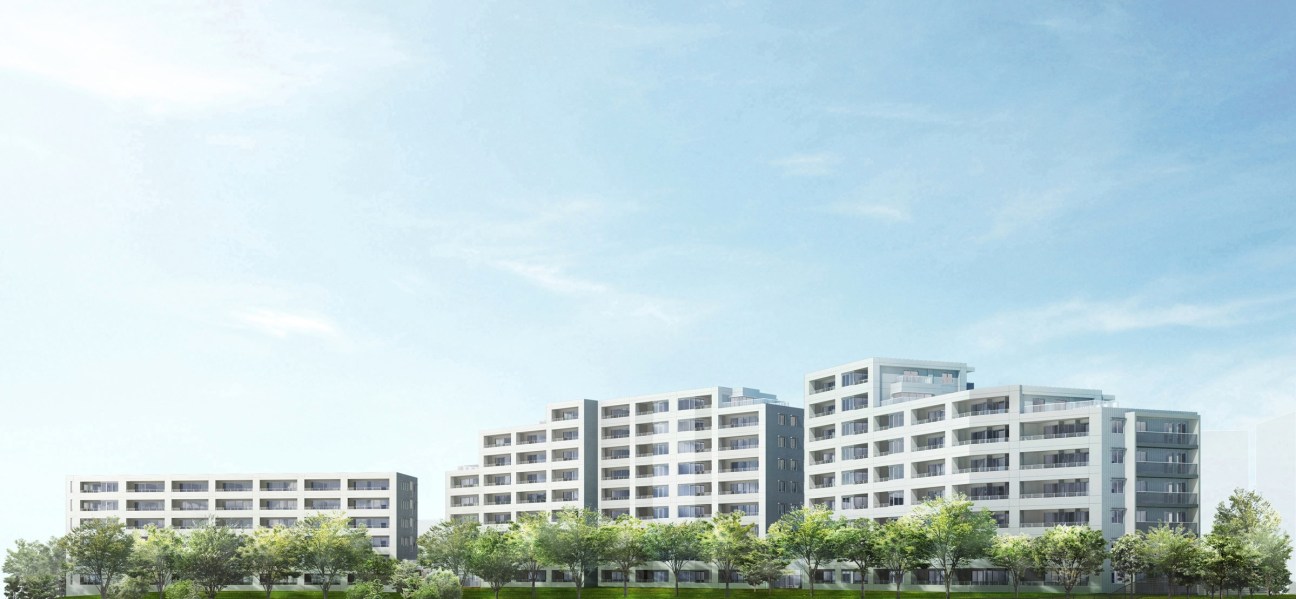 Modern residential apartment complex with white and grey facades under clear blue sky.