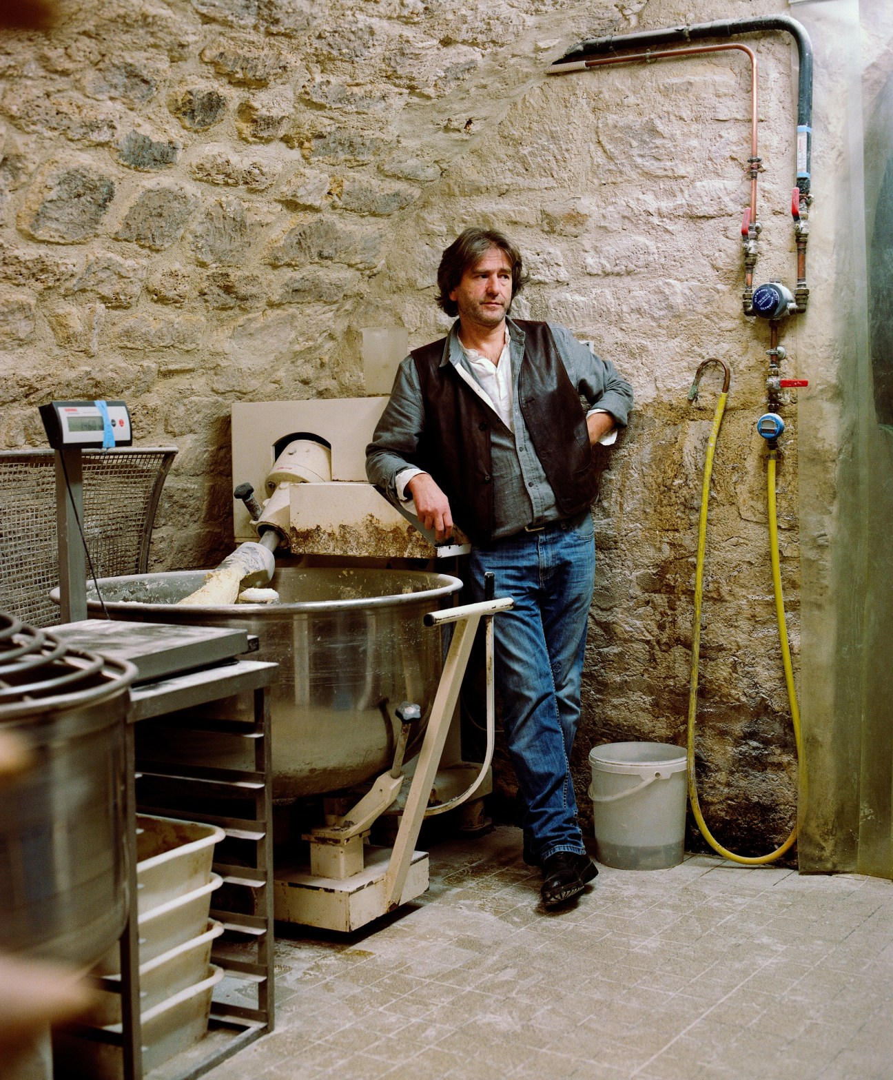 Jean-Luc Poujauran stands in his cellar bread lab surrounded by equipment and pipes.