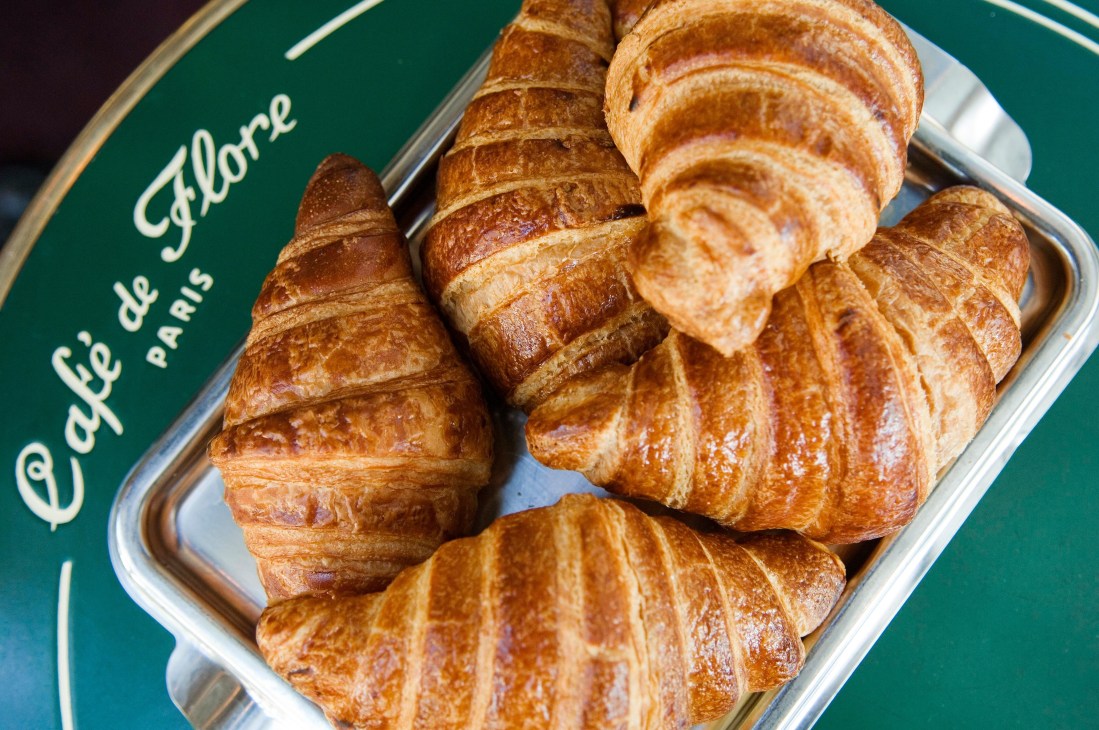 Golden-baked croissants in a Café de Flore branded green tray.