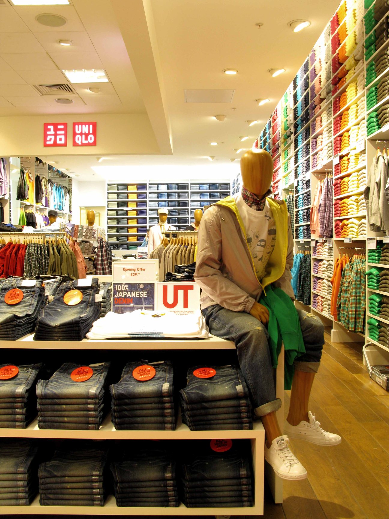 Uniqlo shop-in-shop at Selfridges displaying folded denim jeans and colorful clothing on shelves and racks.