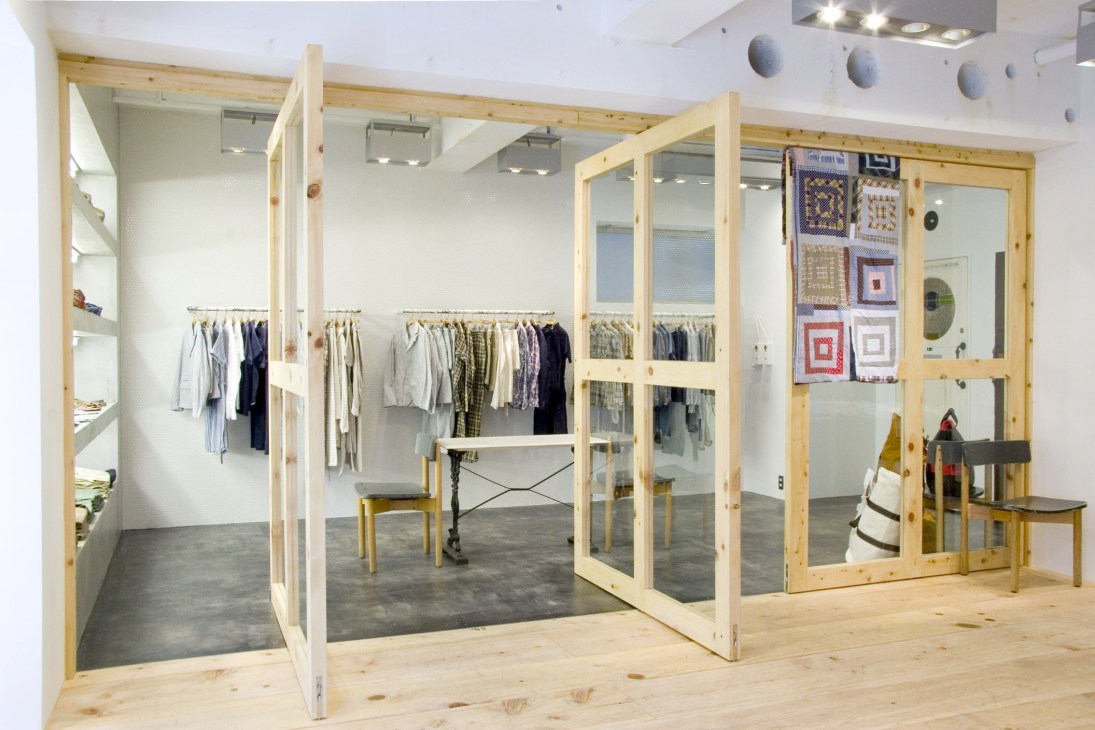 Engineered Garments flagship store interior with wooden frame display cases and clothing racks.