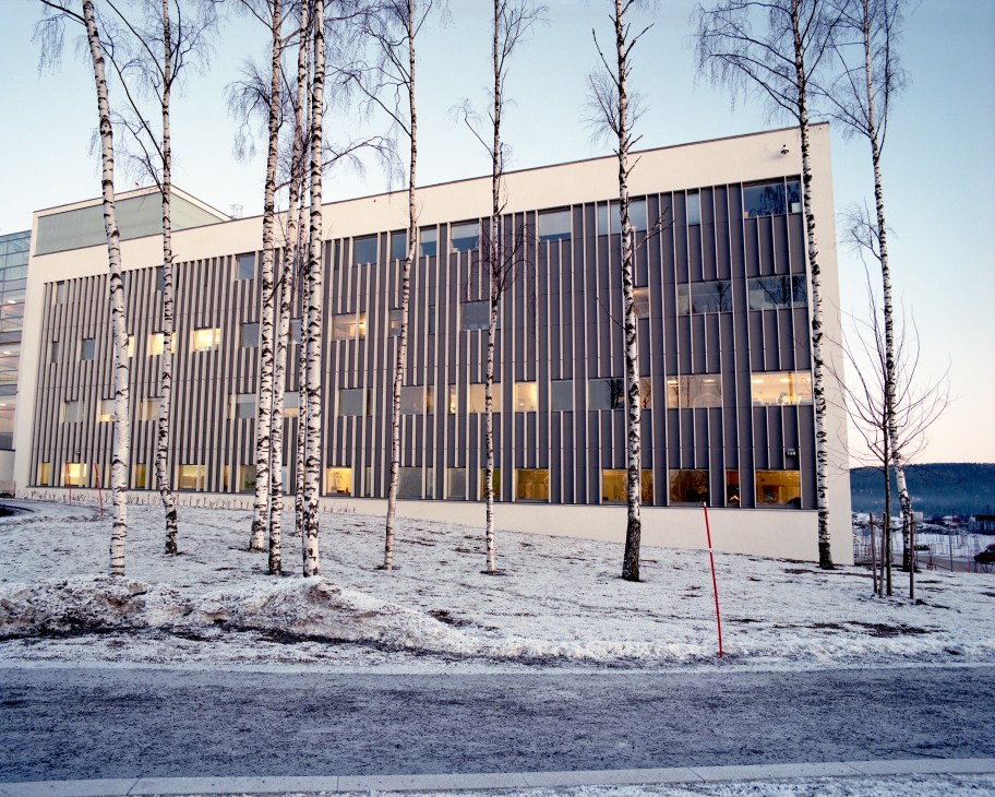 Akershus University Hospital exterior with vertical striping, large windows, and birch trees in foreground.