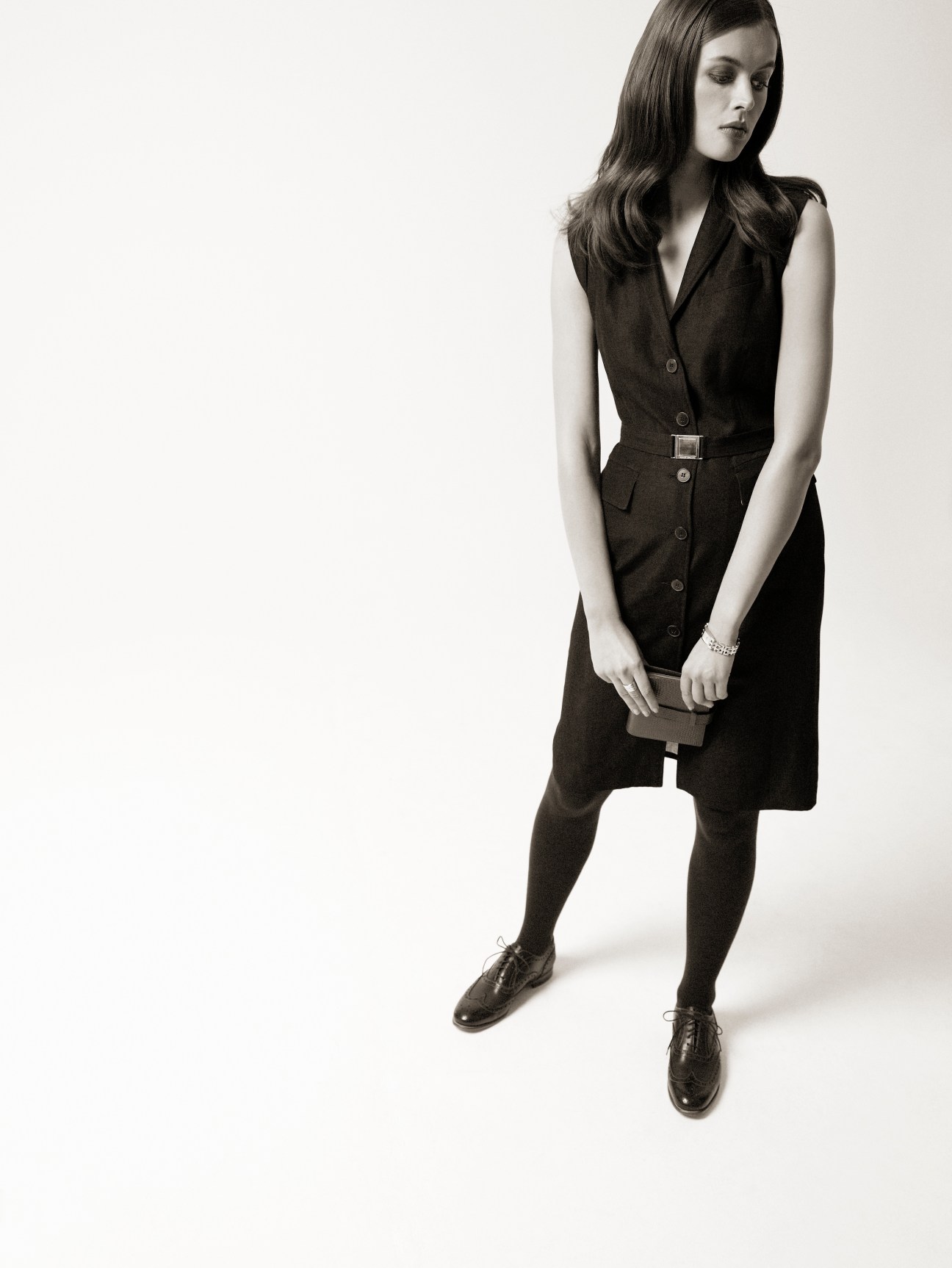 Model wearing sleeveless René Lezard dress with belt, Church's shoes, and holding Smythson diary.