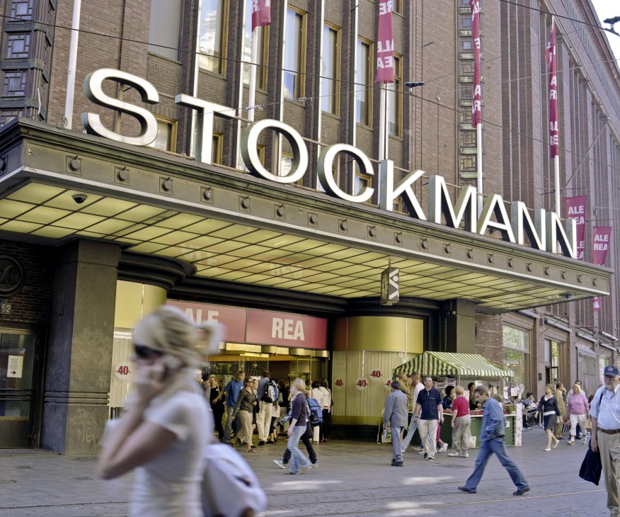 Stockmann department store facade in Helsinki with illuminated signage and shoppers on the street.