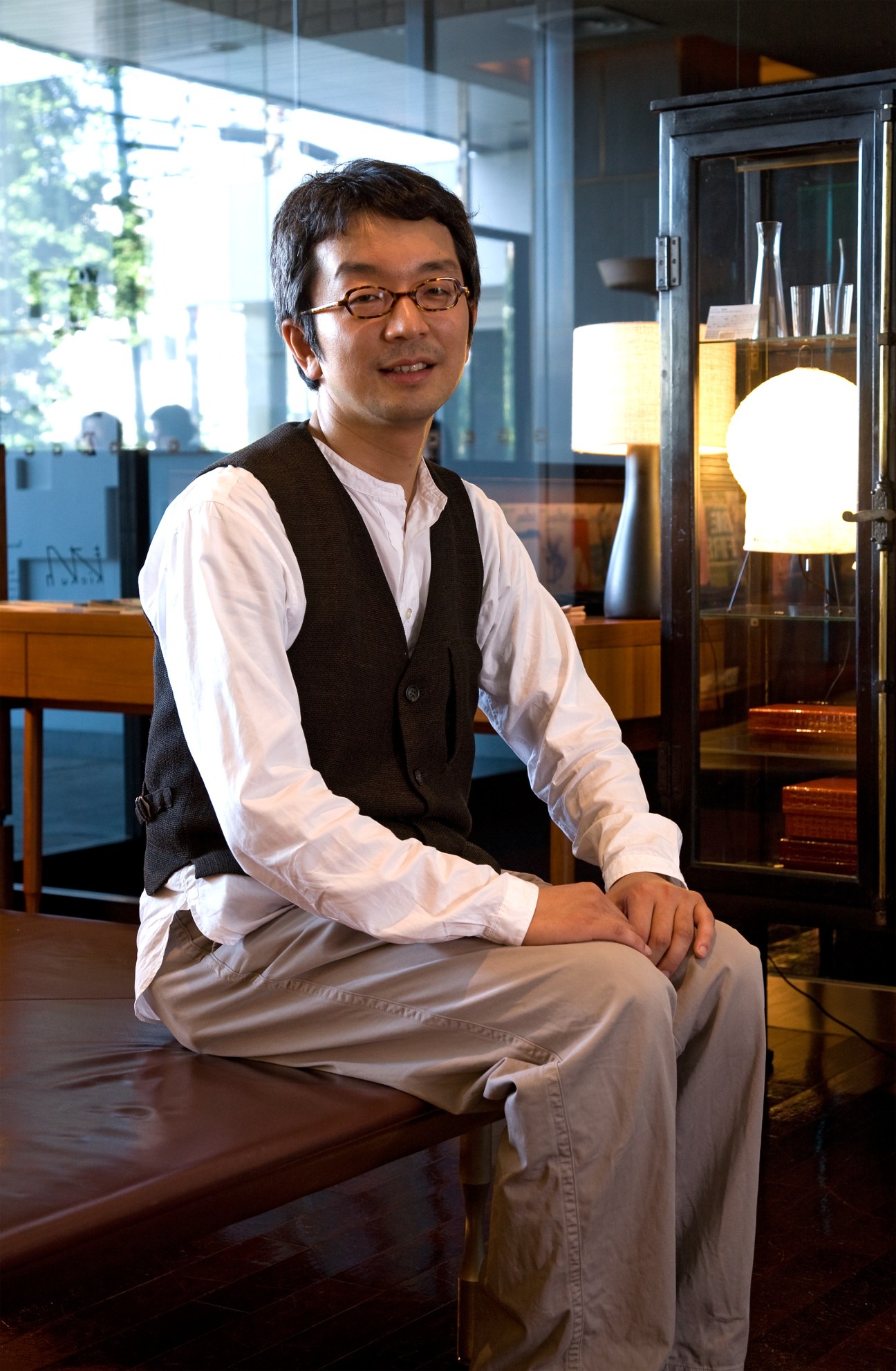 Takeo Okuma, creative director of Claska hotel, sitting in a modern lobby with contemporary lighting and design elements.