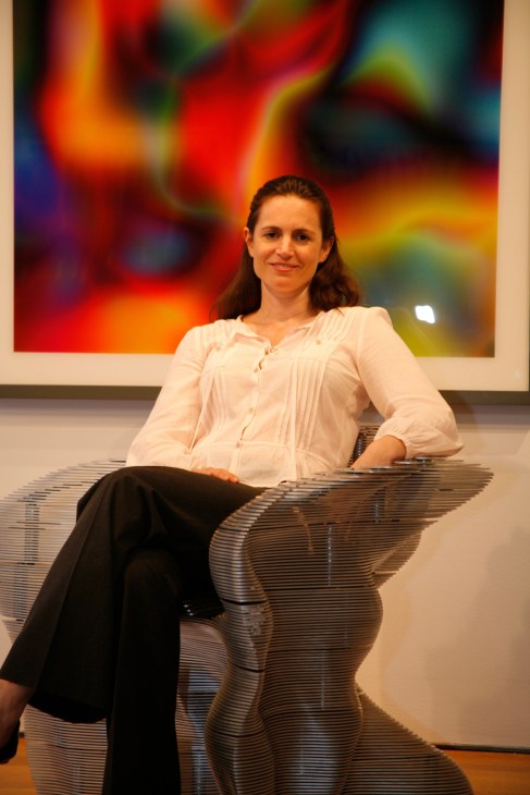 Carina Villinger, Christie's vice president, sitting on a modern metallic bench in front of a colorful abstract artwork.
