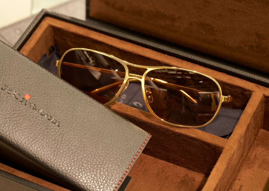 Gold-framed aviator sunglasses by Kiton displayed on a branded leather case.
