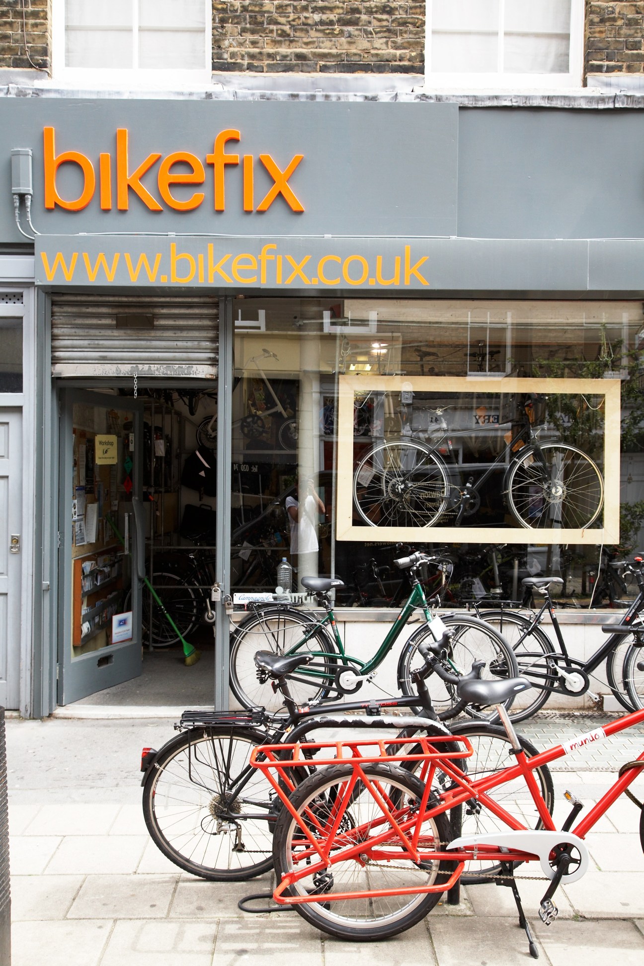 Bikefix bike repair shop storefront with orange signage and bicycles parked outside.