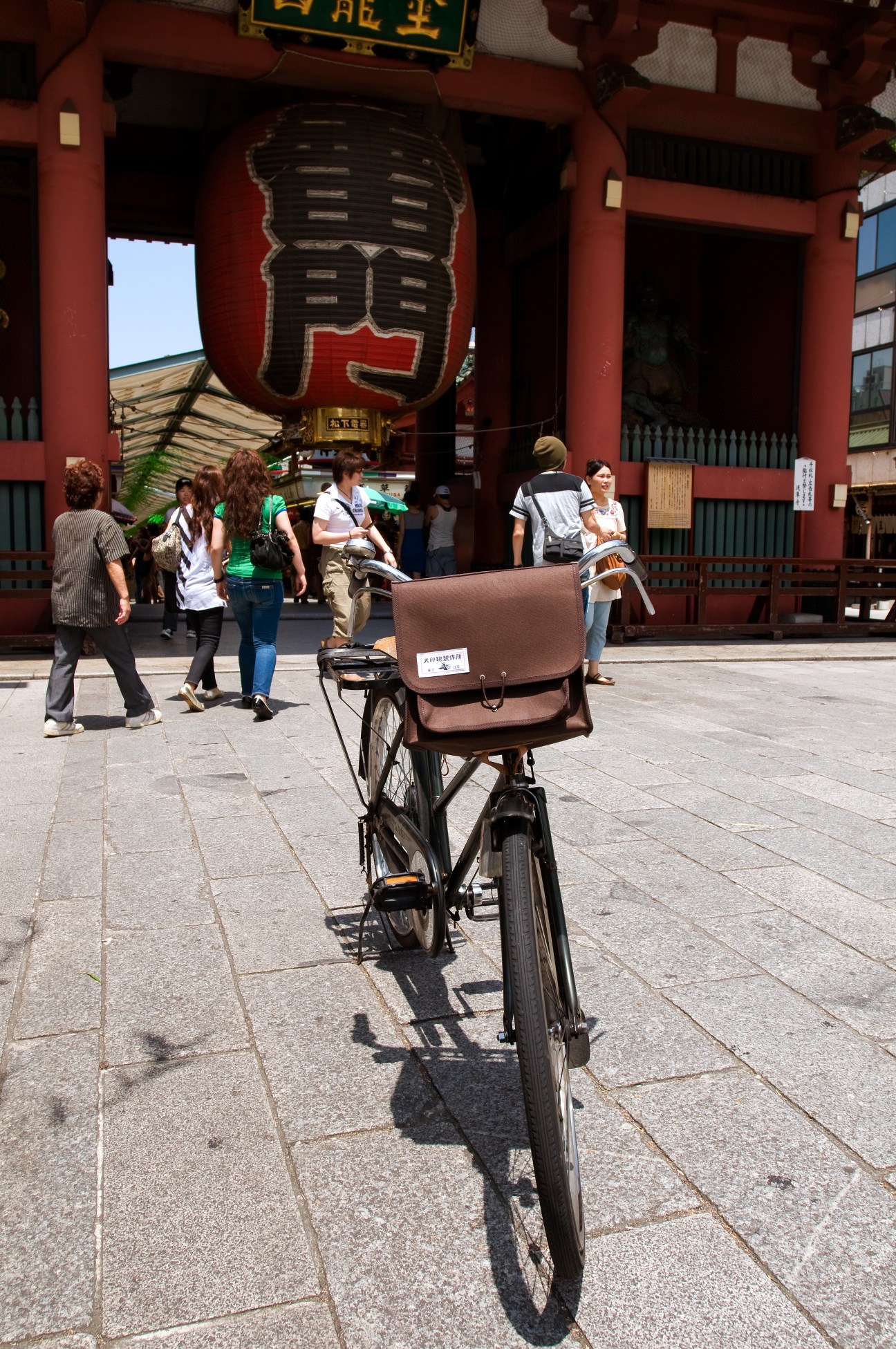 Brown canvas Inujirushi bicycle bag with leather straps mounted on a bike at Sensoji temple in Tokyo.