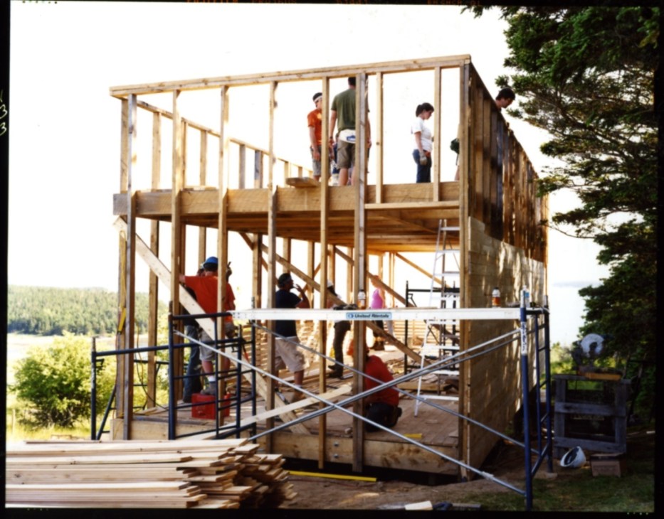 Students and architects work on framing the wooden structure of a two-story building under construction at Ghost Lab.