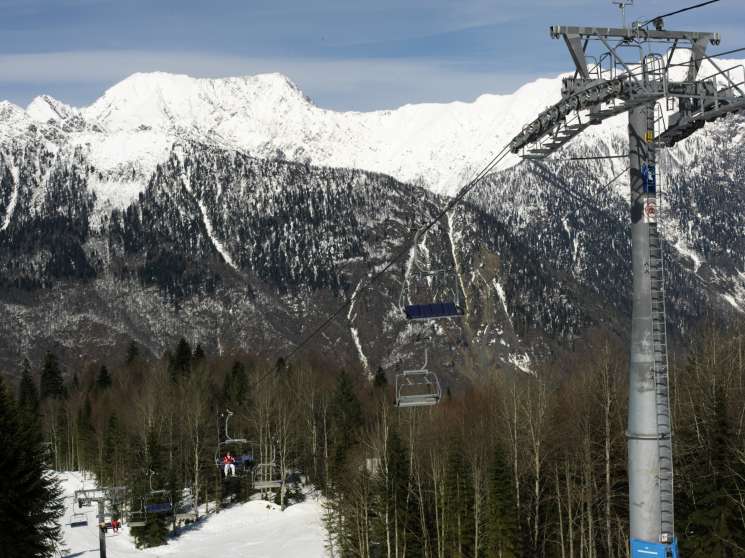 Snow-covered Caucasus mountain peaks with ski lifts and slopes at Krasnaya Polyana resort.