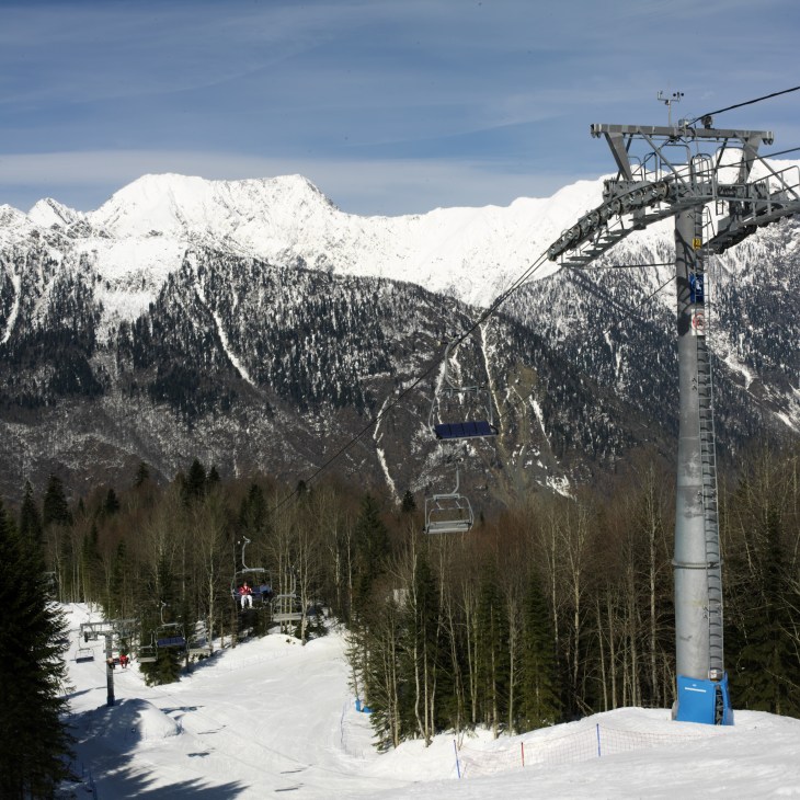 Snow-covered Caucasus mountain peaks with ski lifts and slopes at Krasnaya Polyana resort.