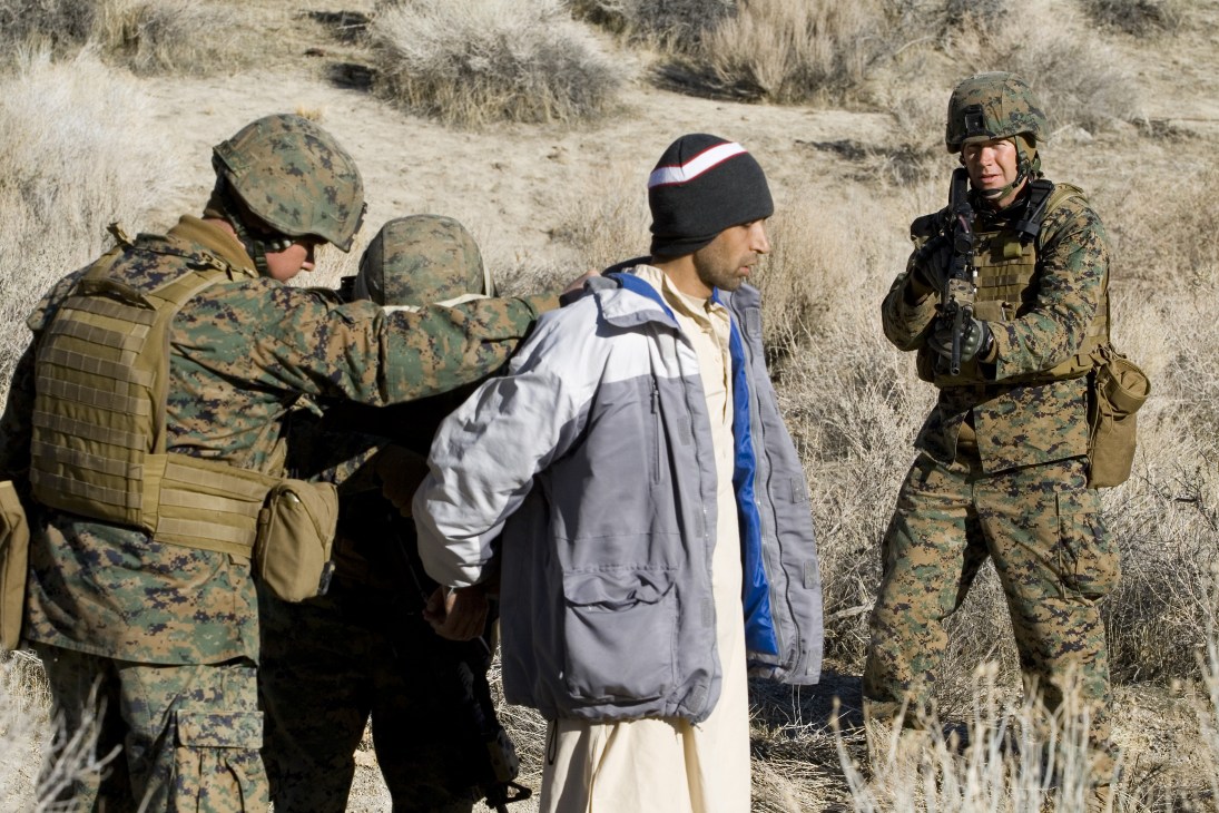 Marines and ANA role players search an Afghan villager in Nevada desert terrain during Mountain Viper training exercise.