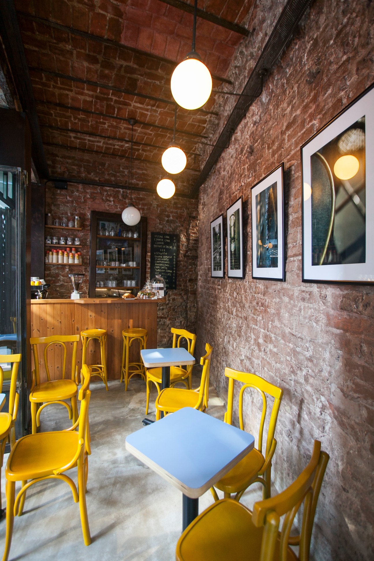 Interior of Nano café with yellow chairs, blue tables, exposed brick walls and pendant lights.