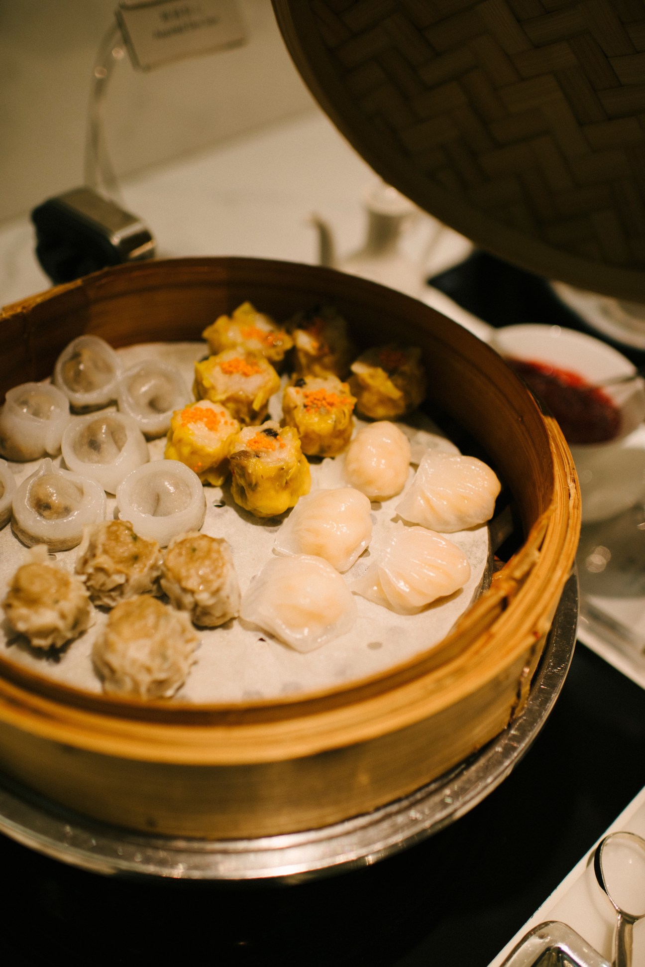 Bamboo steamer basket filled with assorted dim sum dumplings including shrimp and vegetable varieties.