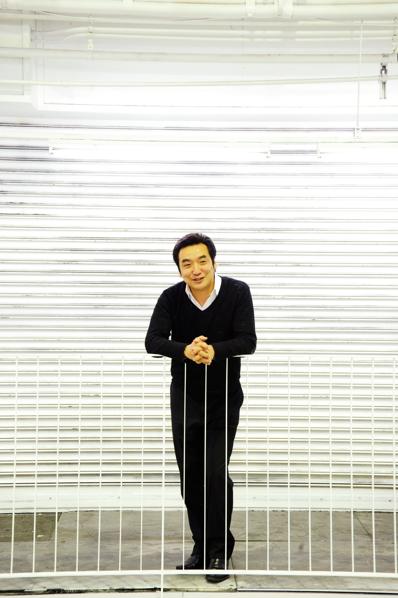 Yasuhiro Harada, producer at Rebita, standing against a white corrugated metal wall.