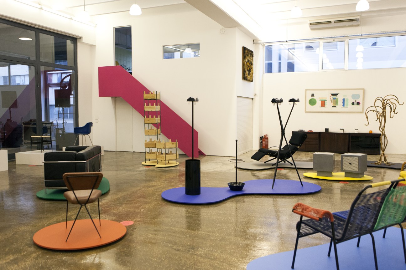 Interior of Karim Bekdache Studio showroom displaying mid-century modern furniture on colorful floor pads with a red staircase.