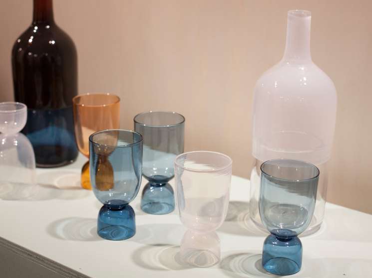 Bottoms Up glasses by Ingrid Aspen in various colors displayed with bottles on a white surface.