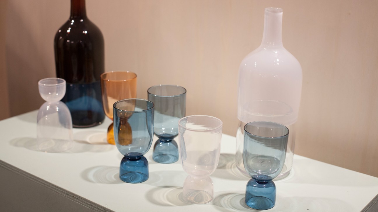 Bottoms Up glasses by Ingrid Aspen in various colors displayed with bottles on a white surface.