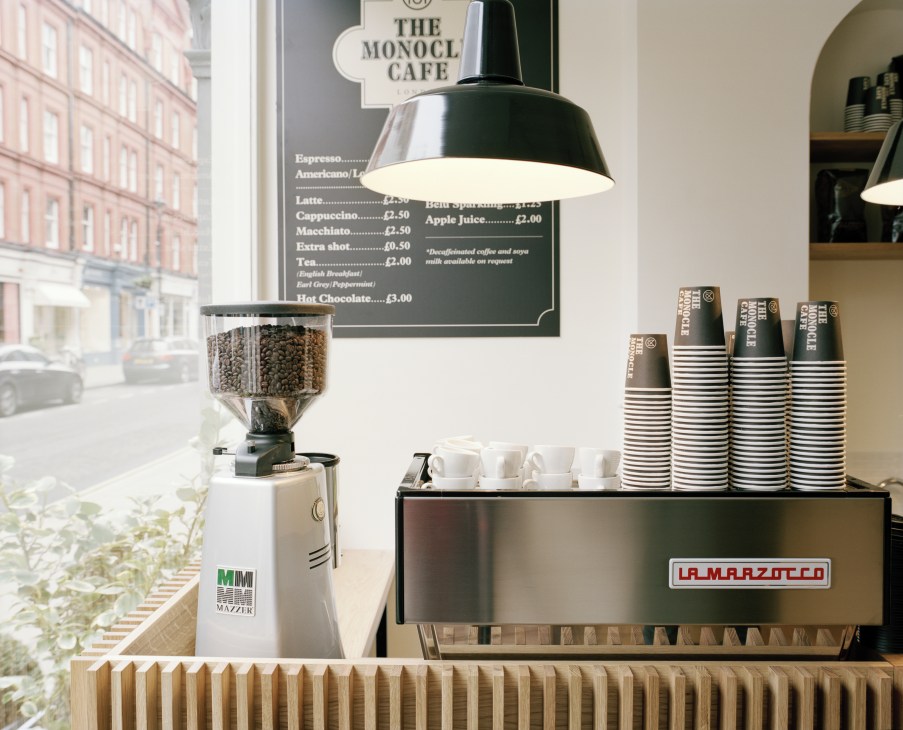 La Marzocco espresso machine with Mazzer grinder and paper cups on Monocle Café counter.