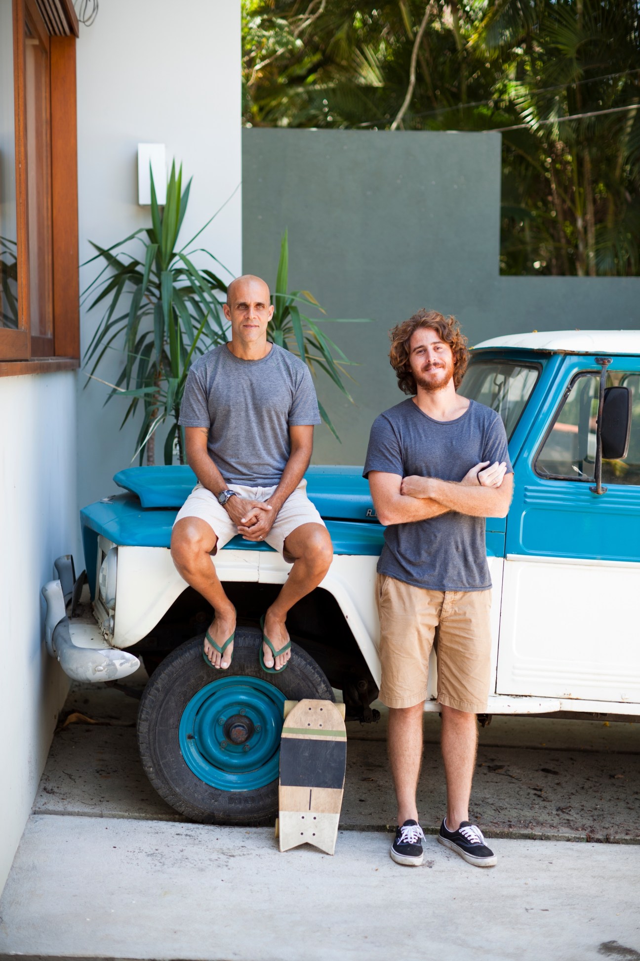 Eduardo Moura and Daniel Olej of Itsu standing with a skateboard and blue truck in their workshop.