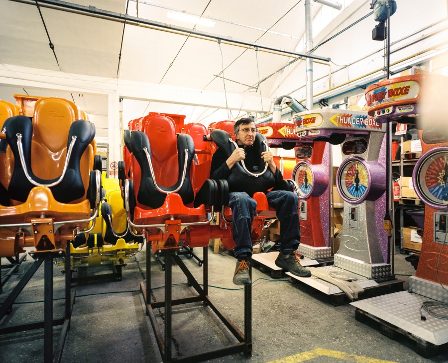 A man sits in a bright red Air Race ride seat at the Zamperla factory in Italy.