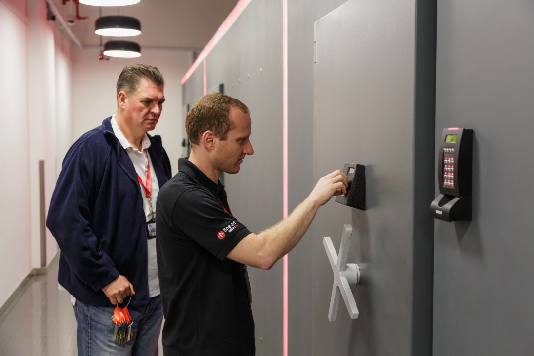 A staff member uses a keycard to access a secure storage unit at Singapore Freeport while a visitor observes.