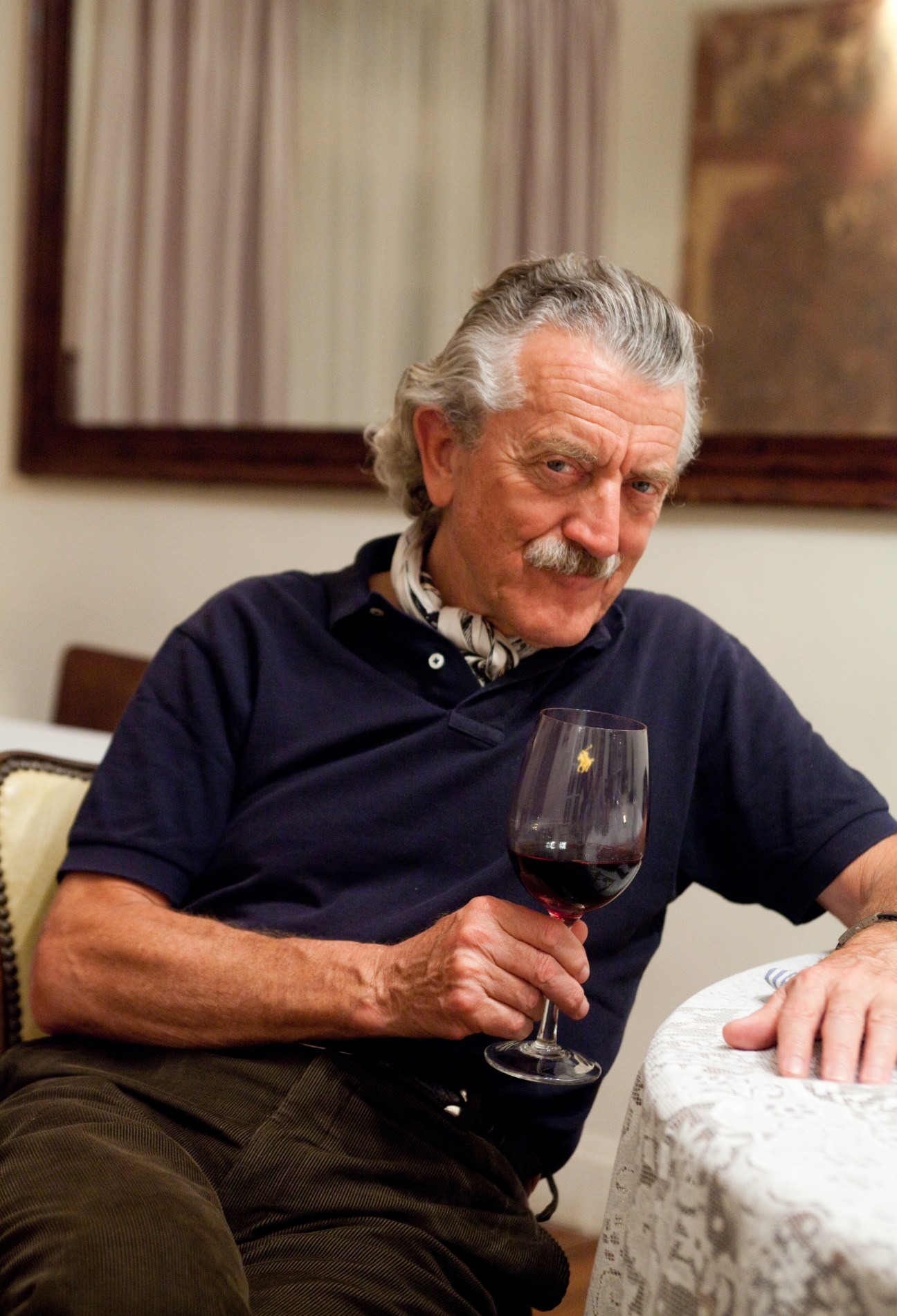 Dieter Meier holding a glass of red wine in his restaurant Ocho Once.