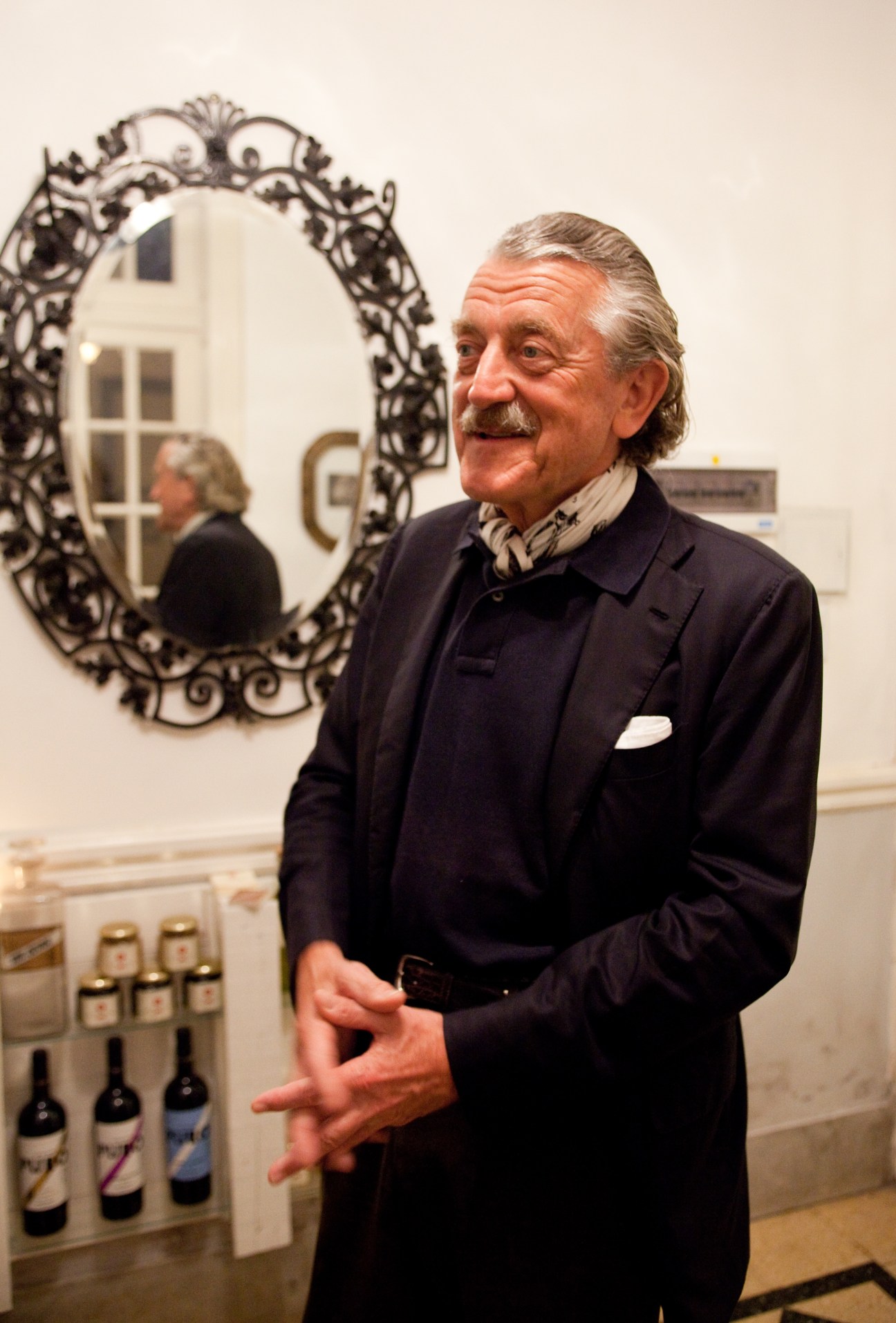 Dieter Meier stands in Ocho Once restaurant beside wine bottles and an ornate mirror.
