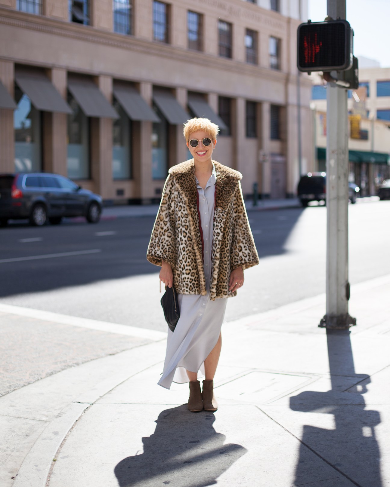 Woman in leopard print cape and sunglasses standing on Downtown LA street