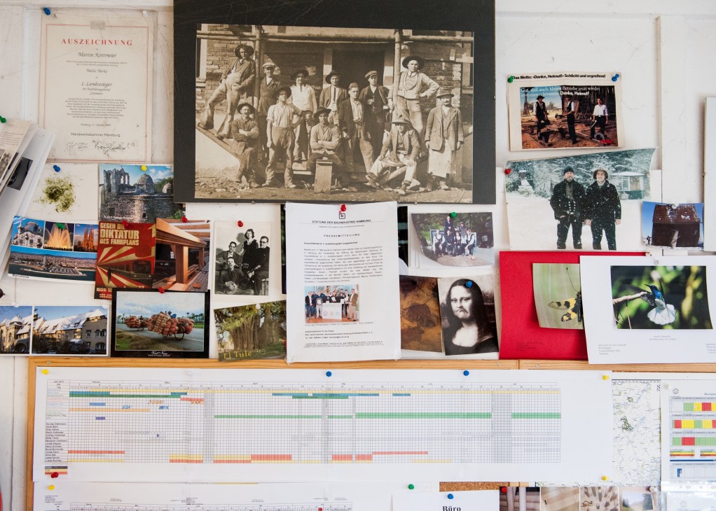 Martin Kottmeier's workshop pinboard displaying photographs, documents, certificates and project planning charts.